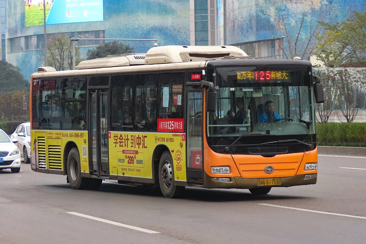 Bas bandar berwarna jingga dengan paparan laluan di sebatang jalan Chongqing.
